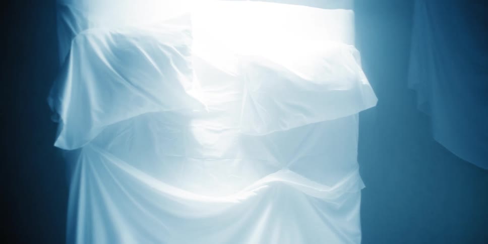 A bed with white linens stand upright in an animation