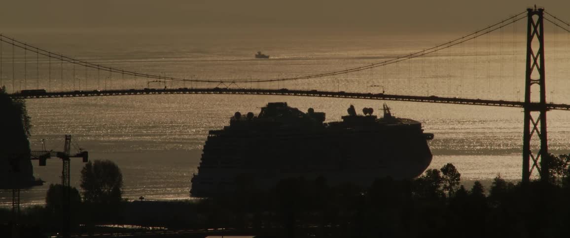 A ship moving across the ocean during sunset