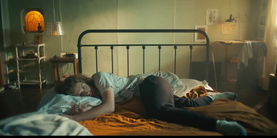 Redheaded man rests on bed as it slides across bedroom toward wall