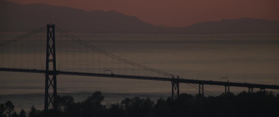 Bridge with moving cars with the sea and mountains on the horizon