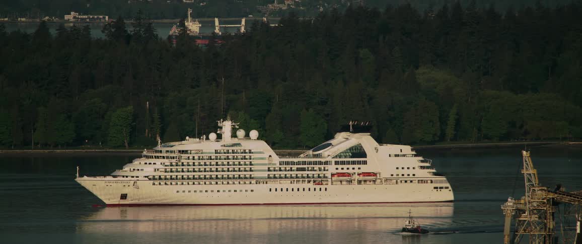 Large cruise ship sailing through a water way with a smaller boat traveling next to it
