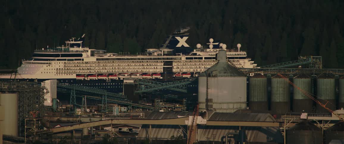 Cruise ship slowly pass near warehouse with tankers sittingon the waterfront