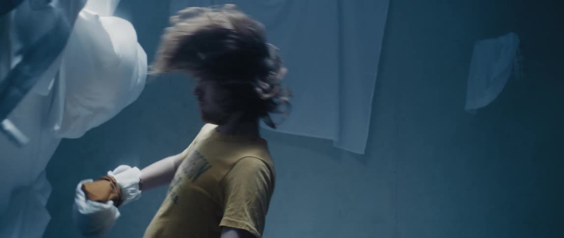 A man standing in a boxing position getting knocked over by a bed