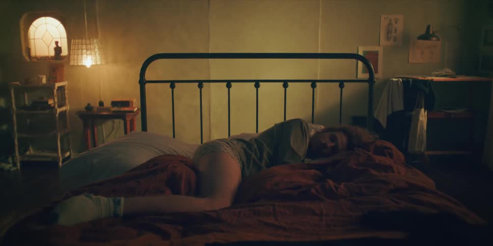 Man laying in bed as the camera zooms in pushing him into the wall