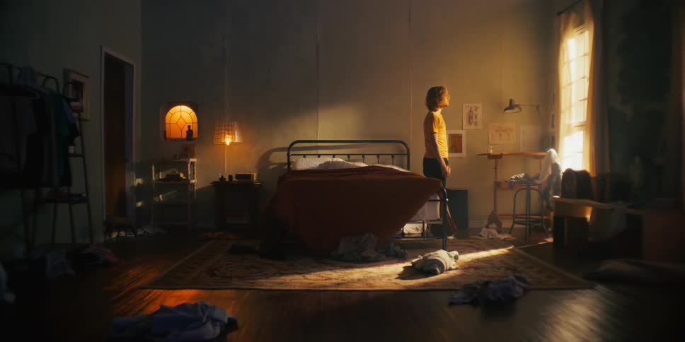 Man getting out of bed and looking around confused as sunlight streams through the window in his messy bedroom