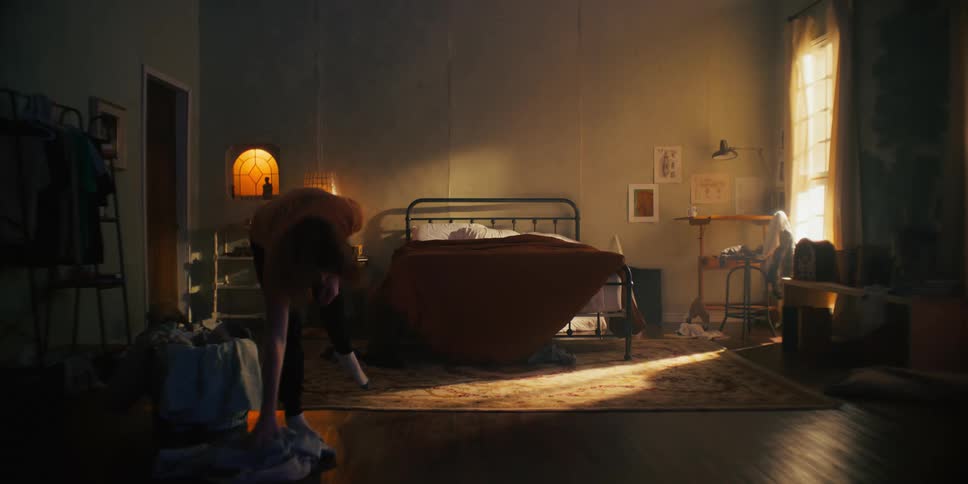 A man looking depressed walking around his room picking up clothes off the floor aggressively before shaking his head in front of a mirror