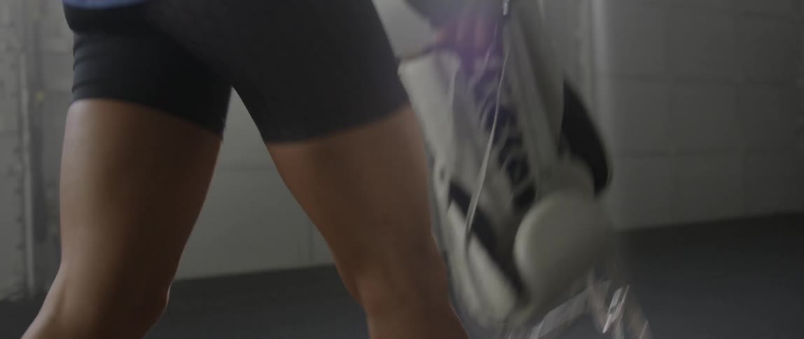 A woman is walking across a room carrying boxing gloves