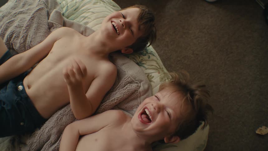 Two young brothers laugh as they lay on their backs on the floor together