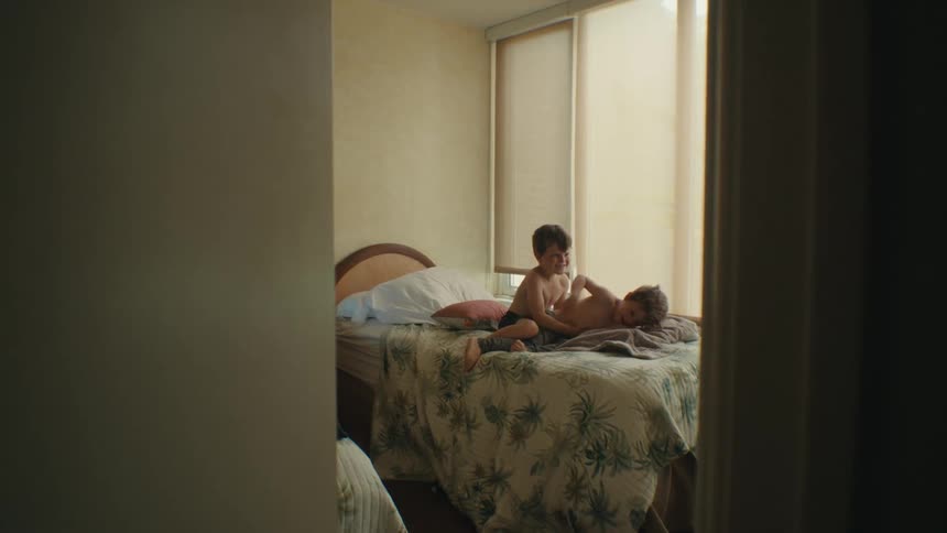 Two boys playing with each other on a bed