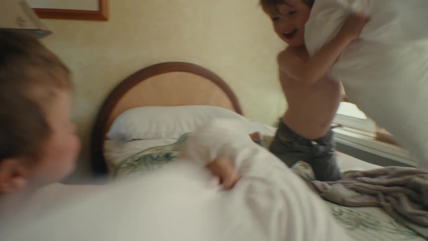 Two boys having a fun pillow fight in a bedroom