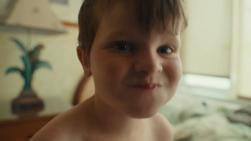 Happy child in the bedroom drinking a water bottle and smiling