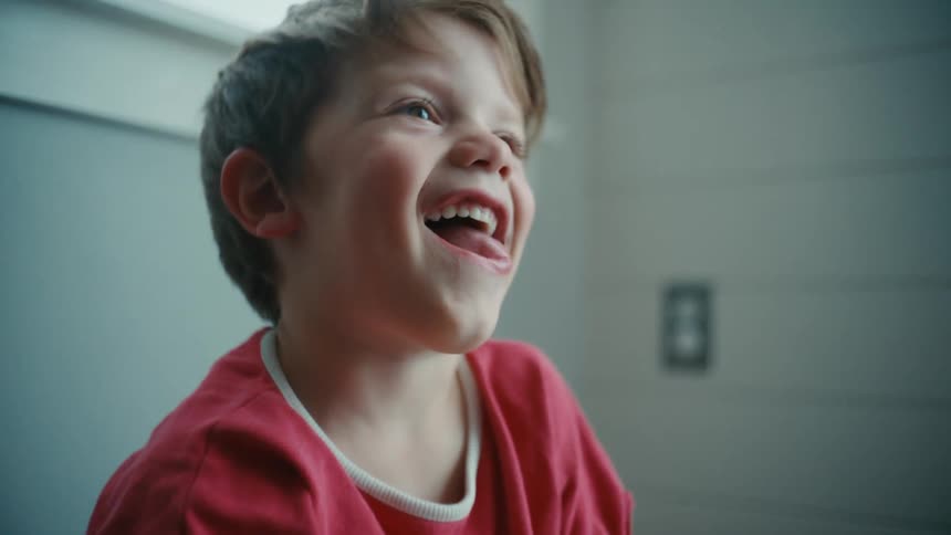 A boy throws his head back while laughing