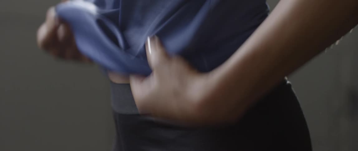 A woman pulls her top down over her torso