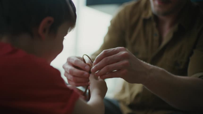 A Patient and loving father instructs his young son in shoe-tying