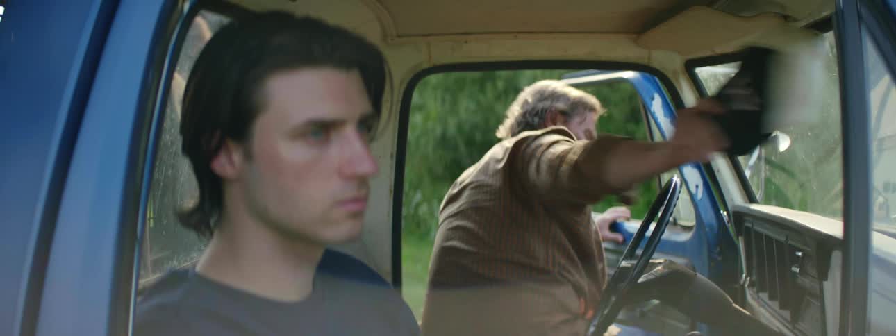 Two men are driving in a car together during spring time