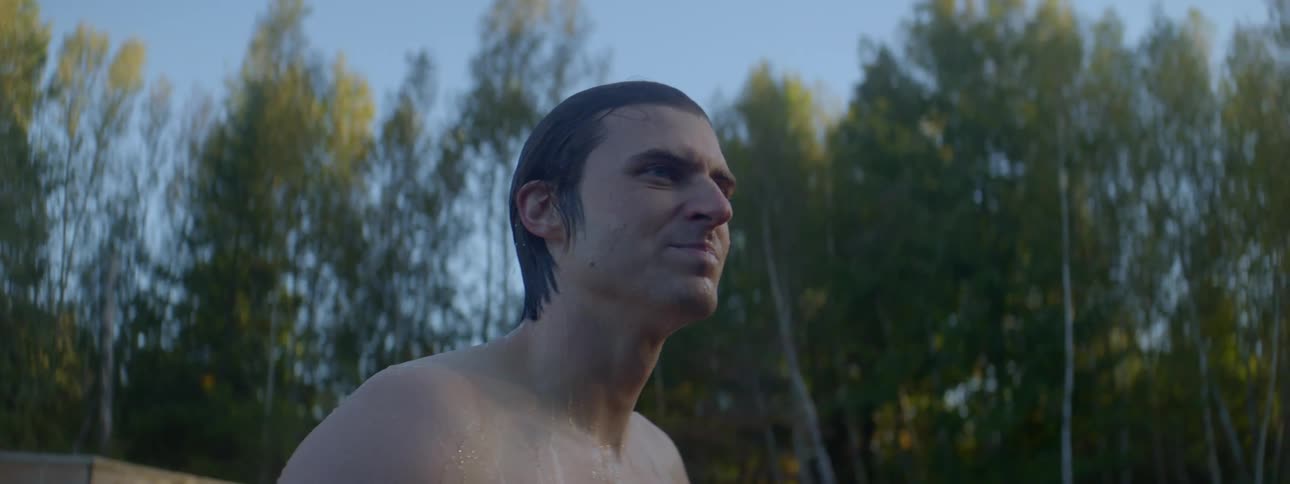 A man comes out from water in a forest lake then swims in it