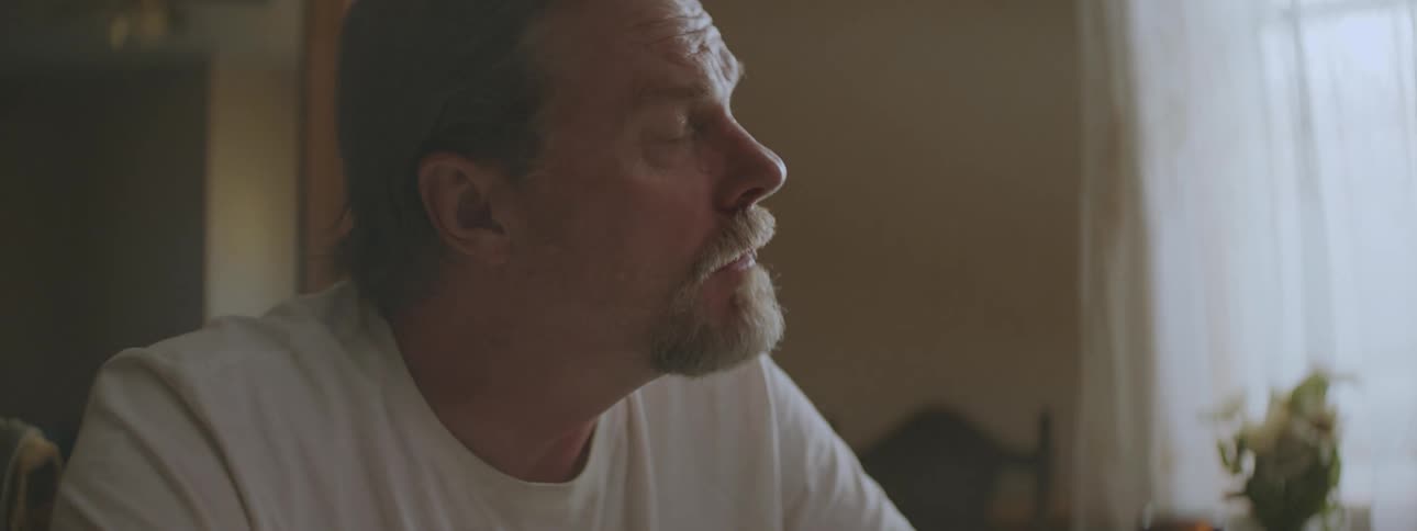 A man is sitting down and drinkinga beer