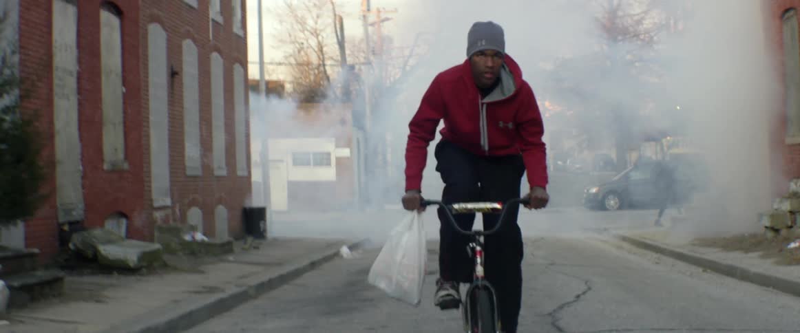 A man bicycles through a smokey street