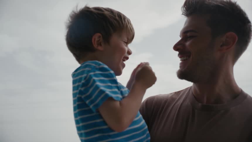 Father and young son sharing a silly moment while laughing together outdoors