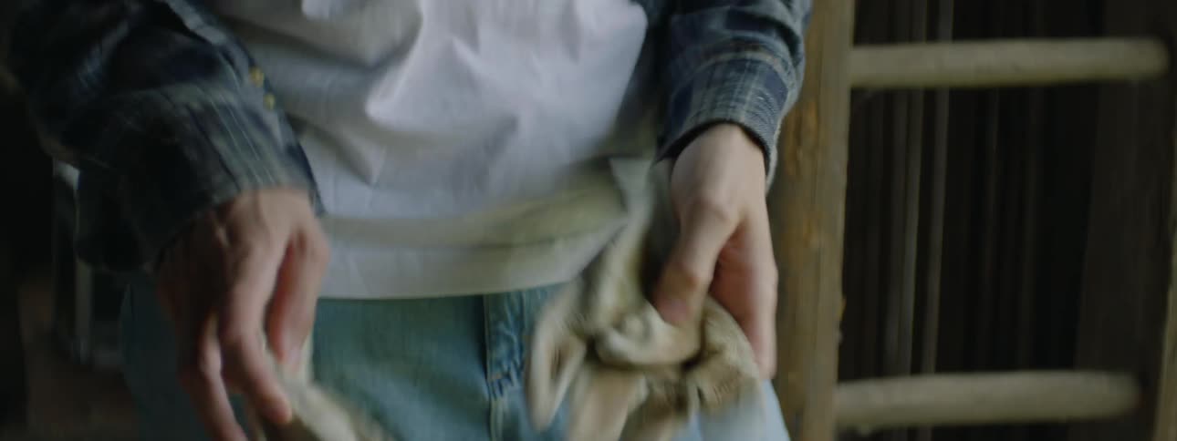 Youth stares out doorway at farm before putting on gloves