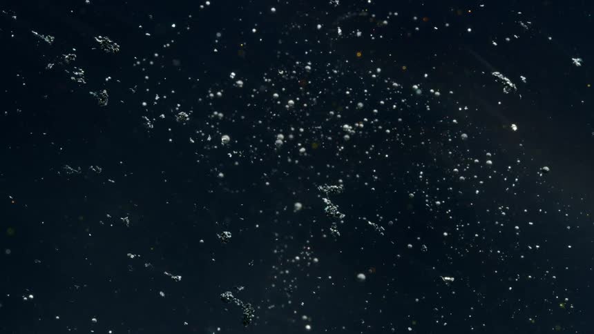 Gray textured particles flow across black background like meteorites through a starfield