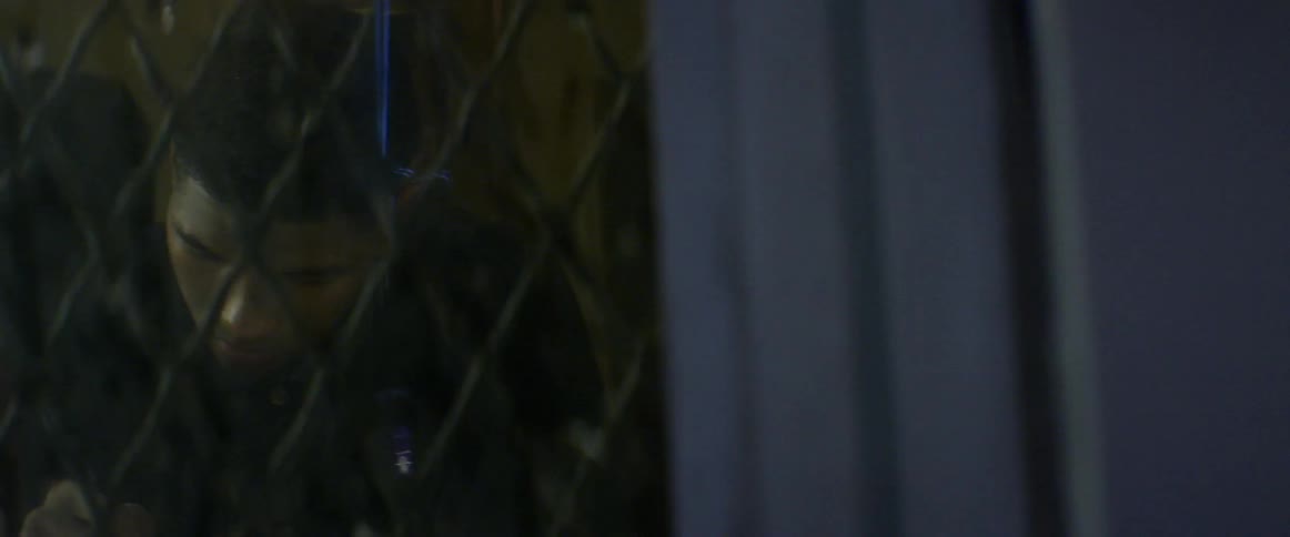 A man is standing behind a gate at night