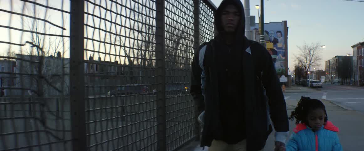 A man is walking along a fence with his child