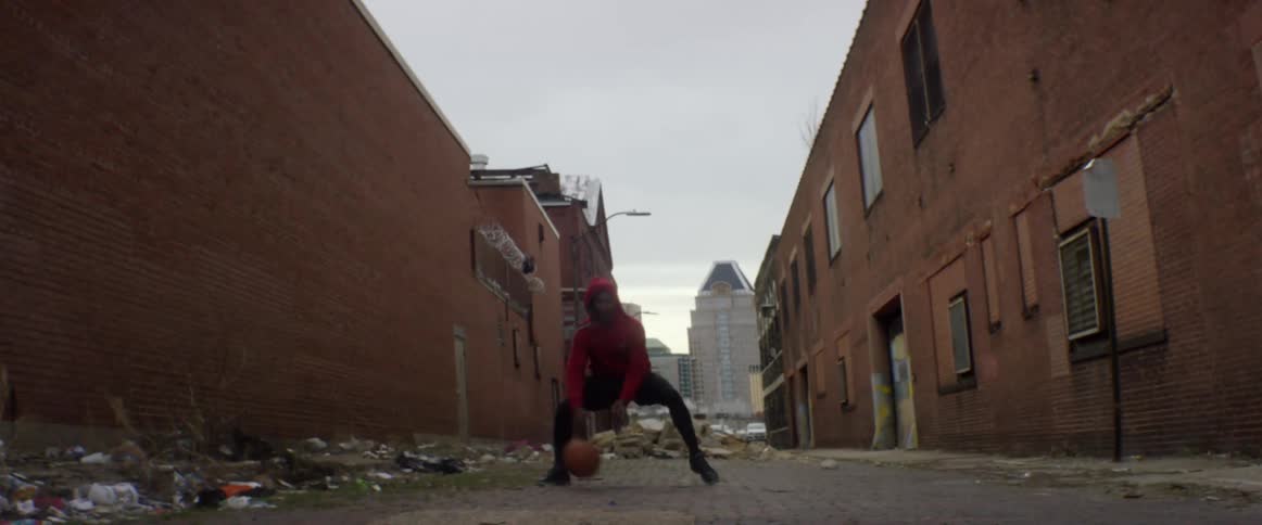A man is dribbling a basketball down an alley