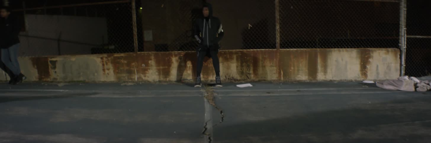 People run across a court as a man sits on the sideline