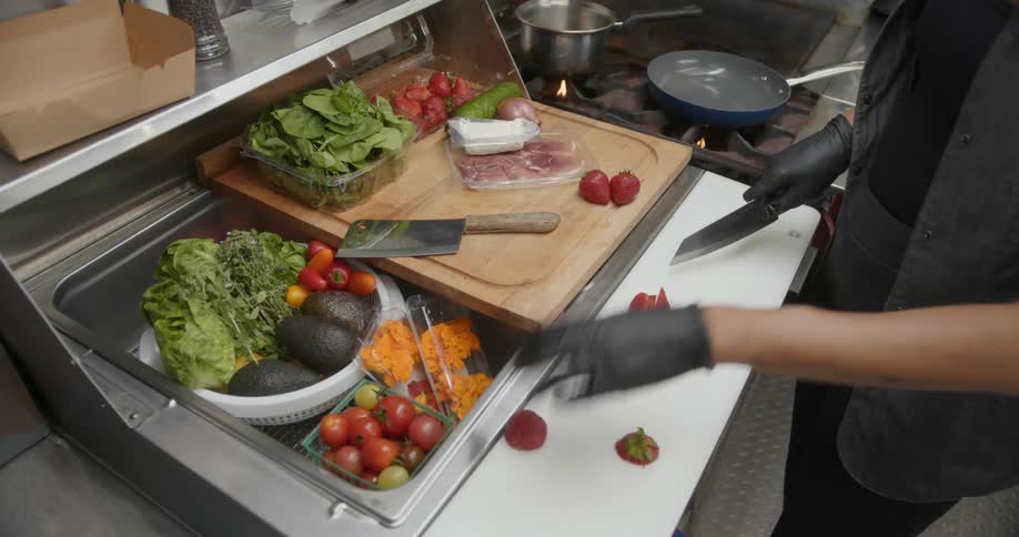 A chef cutting product on a white surface next to a cutting board and stove
