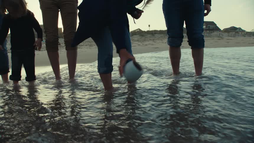 Family with children spreading ashes in the water on the beach in the sand
