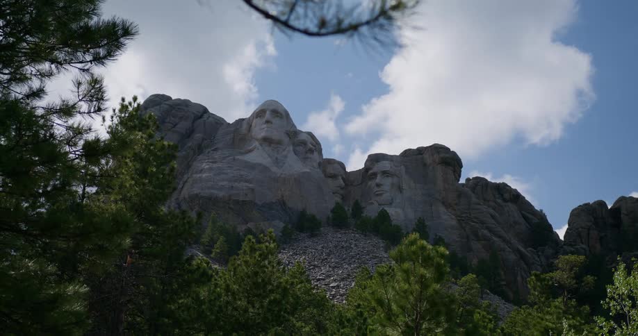 Mount rushmore monument towers over forest under cloudy sky