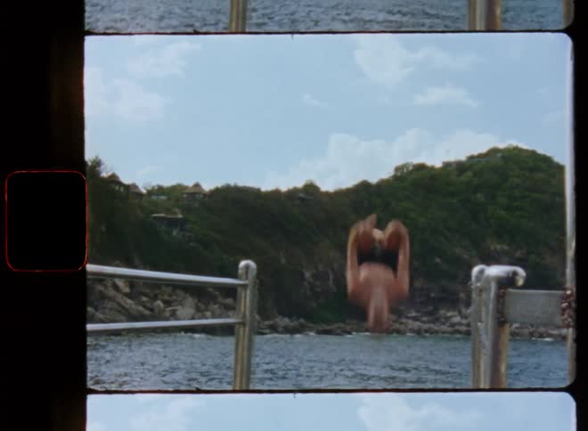 A man does a jumping backflip off a platform into the water below