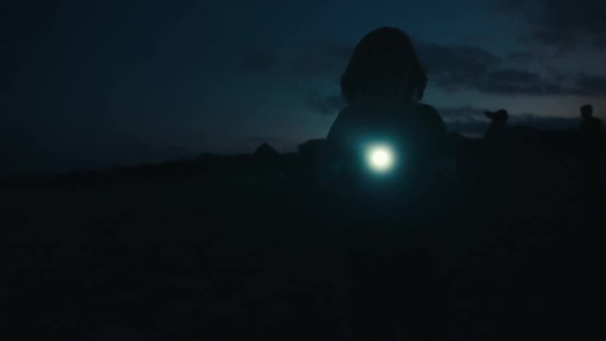 People outdoors at night using flashlights for illumination