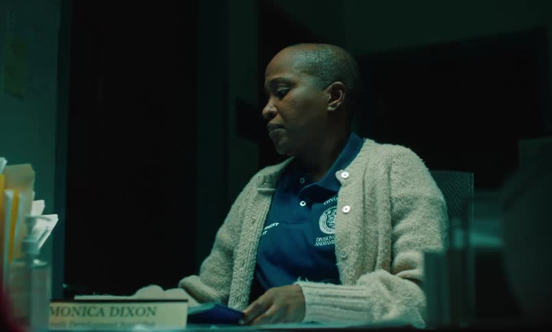 Woman wearing company shirt sighs while working on paperwork
