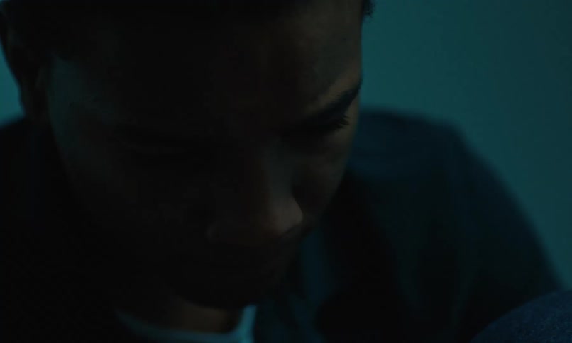 Man sits in dim room thinking while frowning