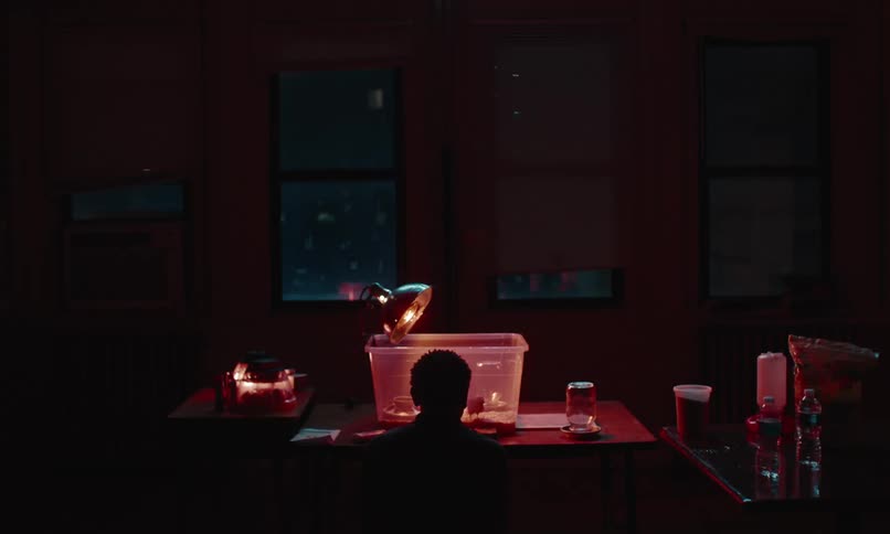 Man sits silhouetted against chick housing under heat lamp