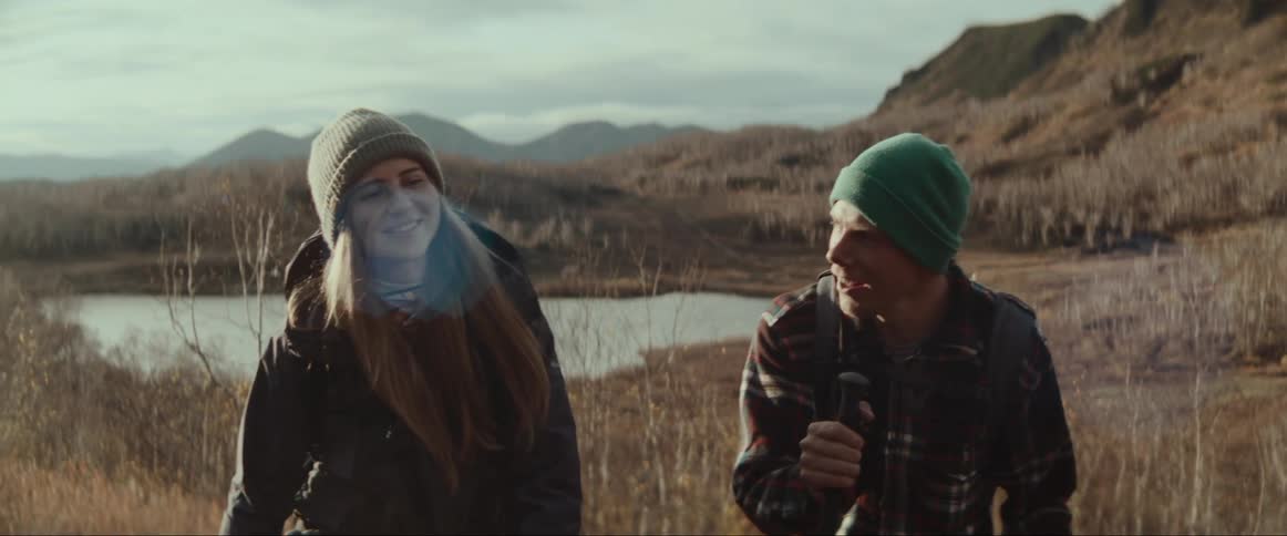 A man and woman talk while hiking through the wilderness during the day