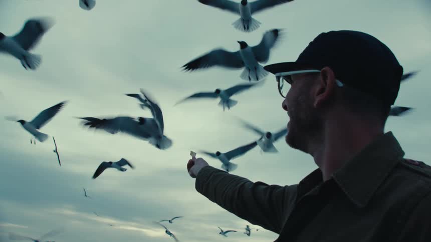A man is outdoors and feeding birds