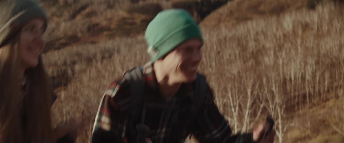 A couple is hiking up a hill and she pushes him