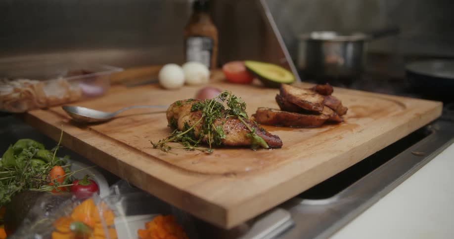A restaurant chef places chicken on a cutting board