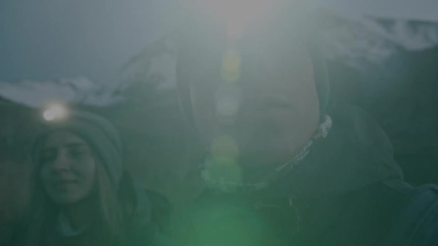 Man and woman are hiking near mountains during the night