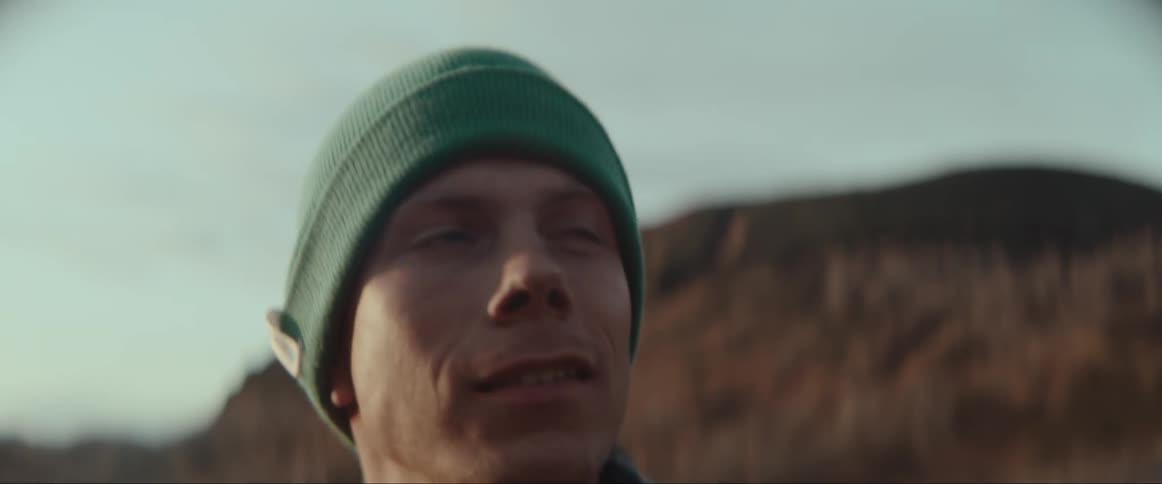 A man hiking outdoors looking around in awe while wearing a green knit cap