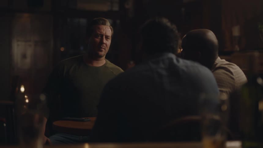 Friends sit together at bar talking then one gets up and walks away