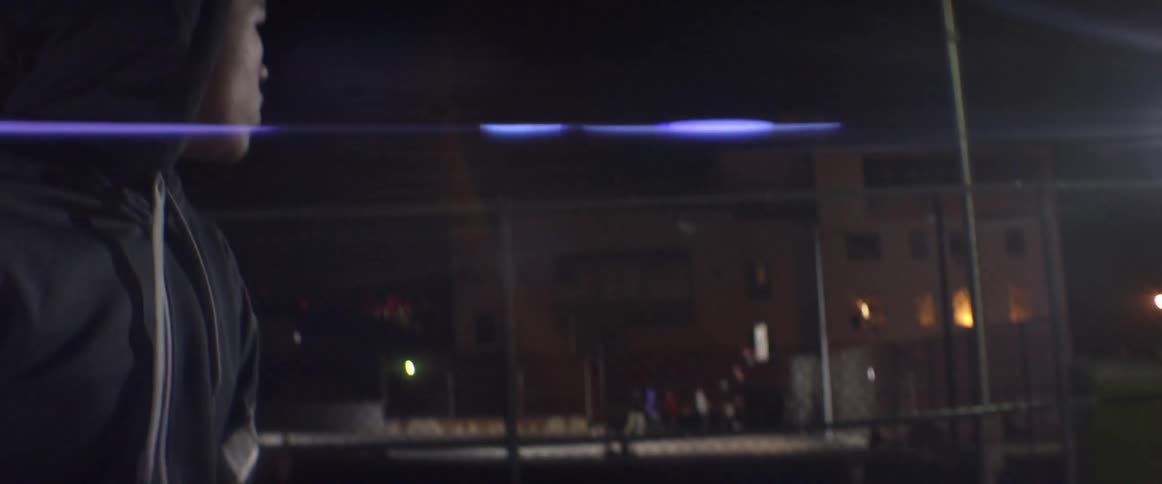 A man looks over to people playing a game of basketball at night