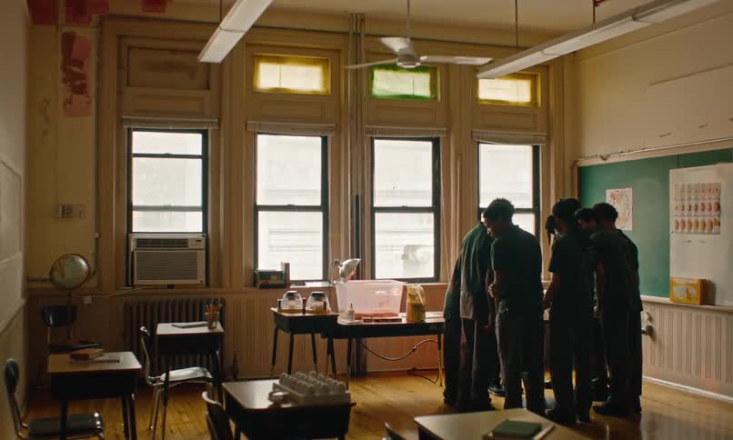 A small group of male students huddled together around a table in a classroom