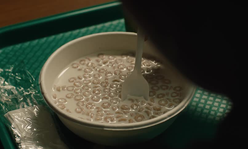 Person moving a plastic spoon in a bowl of cereal with milk