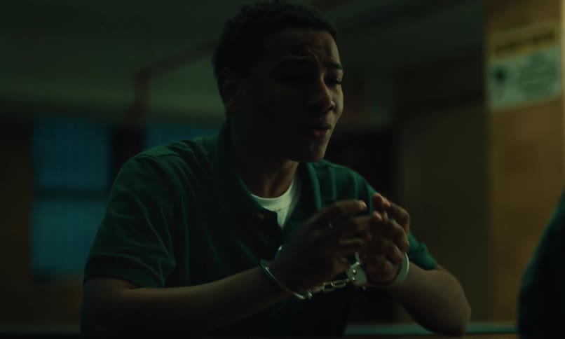 Nervous inmate handcuffed seated at a table talking to someone else