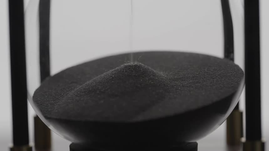 Black sand falling inside an hourglass