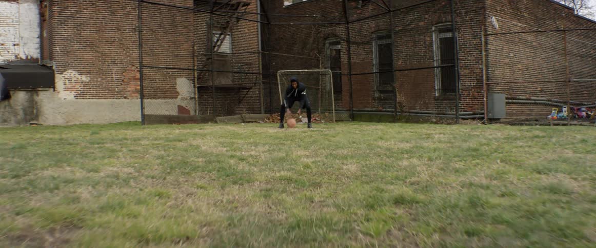 Man dribbles a ball in front of a goal net